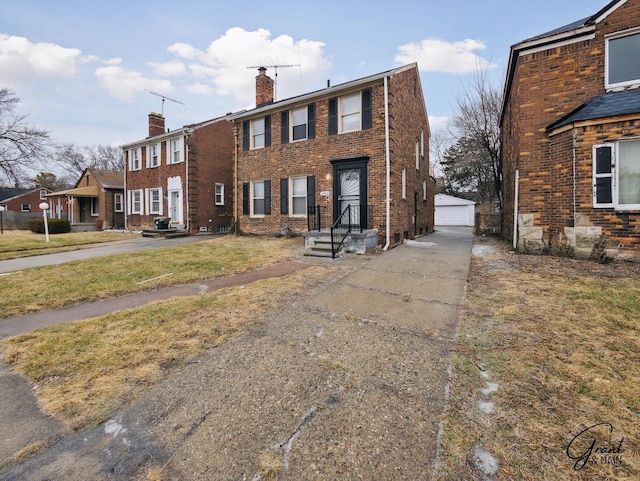 view of front of house featuring a garage, brick siding, a chimney, and an outbuilding