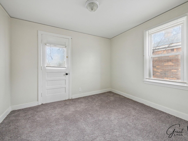 carpeted spare room with a healthy amount of sunlight and baseboards