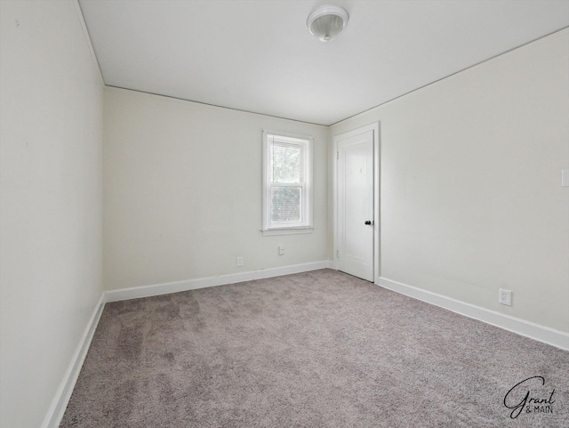 unfurnished room featuring carpet and baseboards