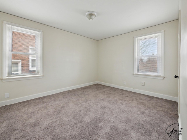 carpeted empty room featuring baseboards