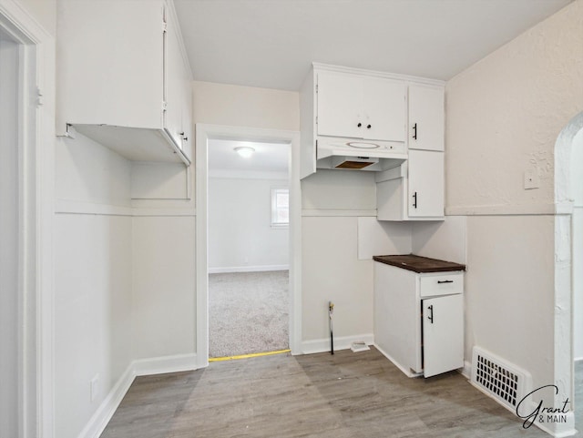 kitchen with white cabinets, visible vents, light wood-style flooring, and baseboards