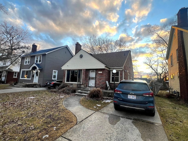 view of front of house with brick siding, a chimney, and a shingled roof