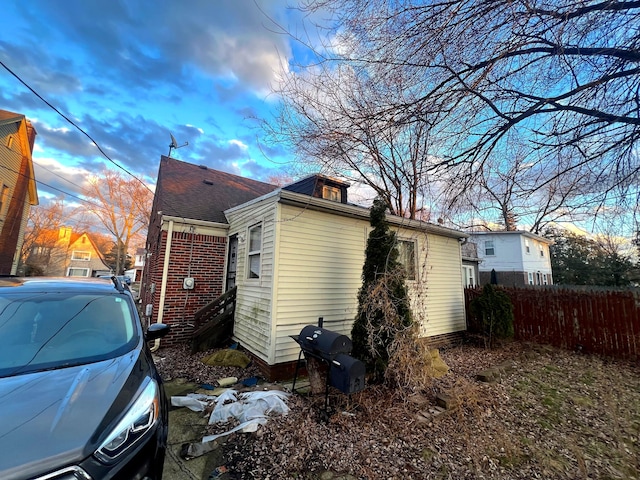 view of side of property with brick siding and fence