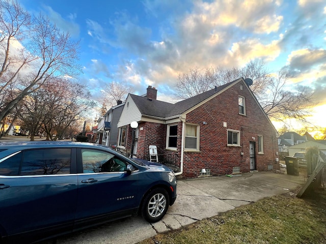 view of property exterior featuring roof with shingles, a chimney, and brick siding