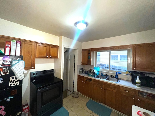 kitchen with light tile patterned floors, a sink, light countertops, black appliances, and brown cabinetry