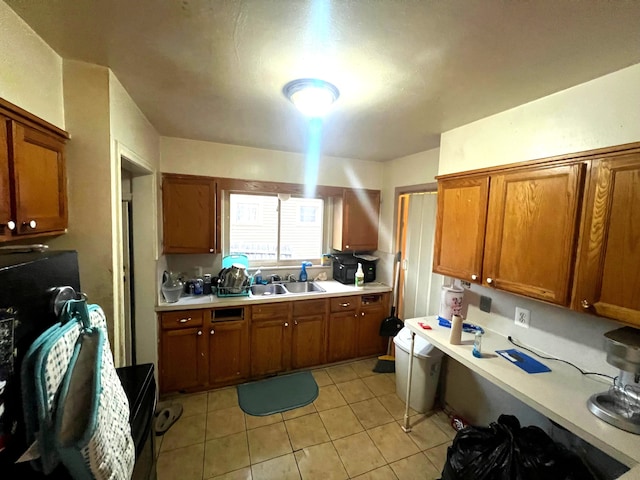 kitchen with a sink, brown cabinets, light countertops, and light tile patterned flooring