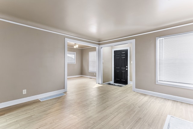 unfurnished room featuring light wood-type flooring, visible vents, and baseboards