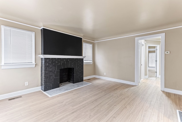 unfurnished living room featuring light wood-type flooring, a brick fireplace, visible vents, and baseboards