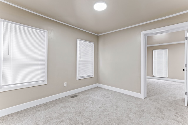 carpeted spare room with visible vents, crown molding, and baseboards