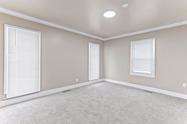 spare room featuring baseboards, carpet floors, visible vents, and crown molding