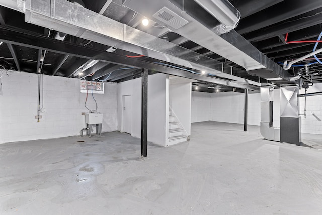 unfinished basement featuring stairway, visible vents, and heating unit