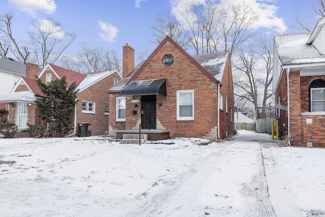 bungalow-style home with brick siding and a chimney