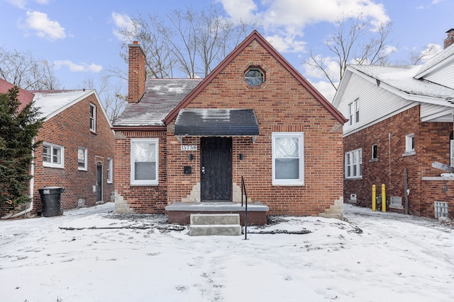 bungalow-style house featuring a chimney and brick siding