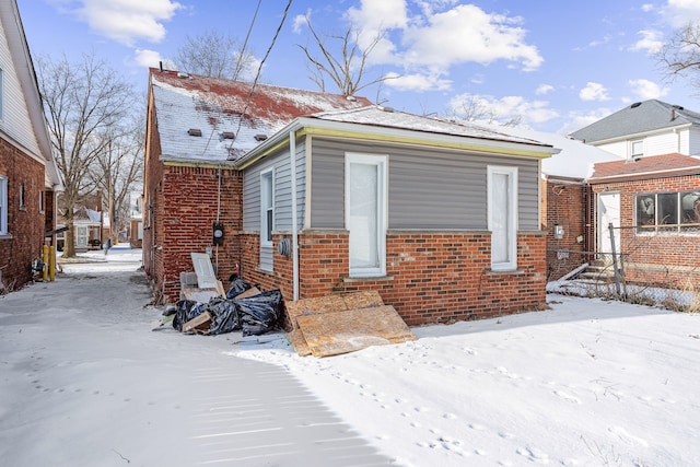 view of snowy exterior with brick siding