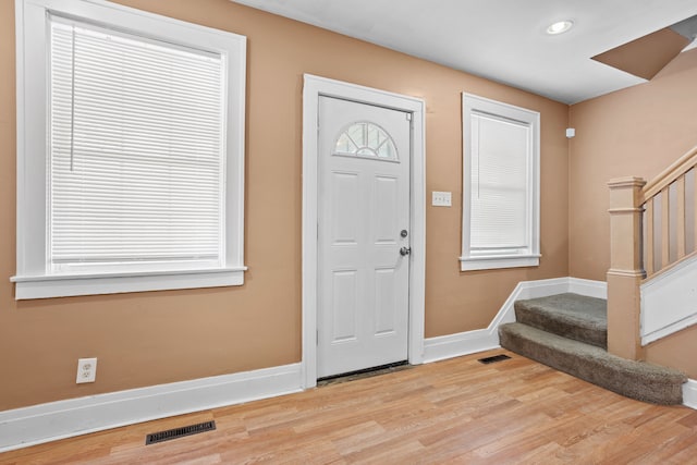 foyer entrance with stairway, wood finished floors, visible vents, baseboards, and a wealth of natural light