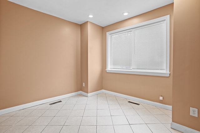 empty room with light tile patterned floors, baseboards, and visible vents