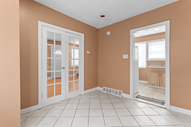 interior space with light tile patterned floors, visible vents, french doors, and baseboards