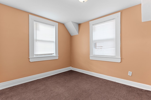 additional living space featuring baseboards and dark colored carpet