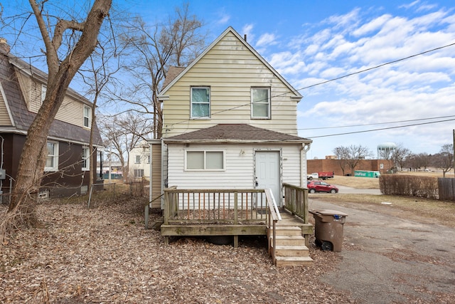 back of property with roof with shingles and fence