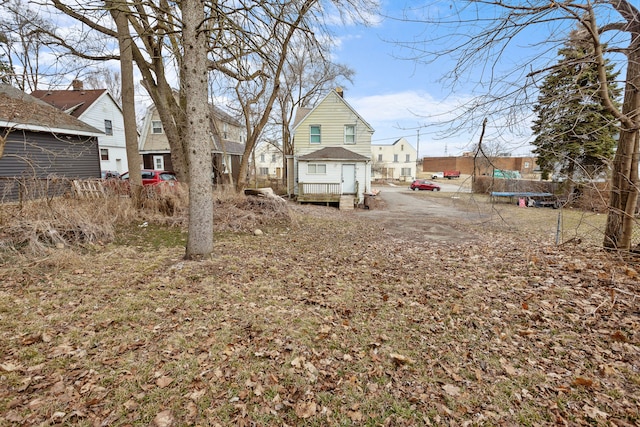 view of yard featuring a residential view, a trampoline, and fence