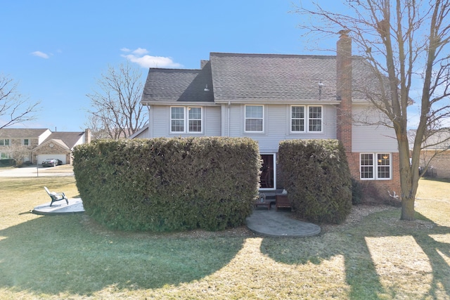 view of front of property featuring entry steps, a front yard, a shingled roof, brick siding, and a chimney