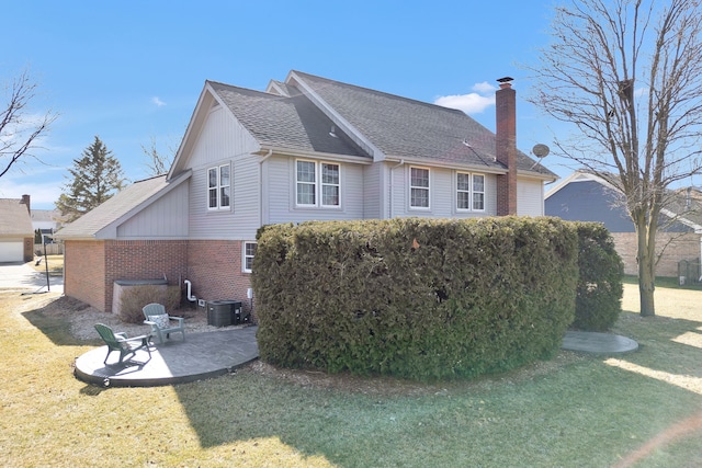 view of property exterior featuring roof with shingles, a yard, a chimney, a patio area, and brick siding