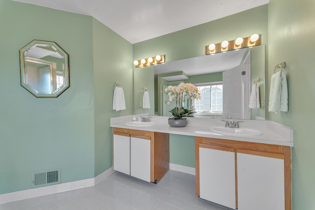 bathroom with double vanity, baseboards, visible vents, and a sink