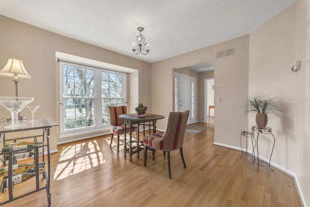 dining space featuring visible vents, baseboards, a chandelier, and light wood finished floors