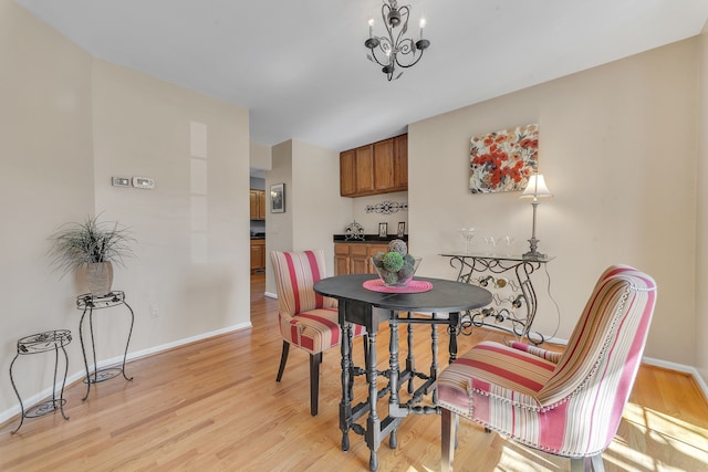 dining area featuring baseboards, a chandelier, and light wood finished floors