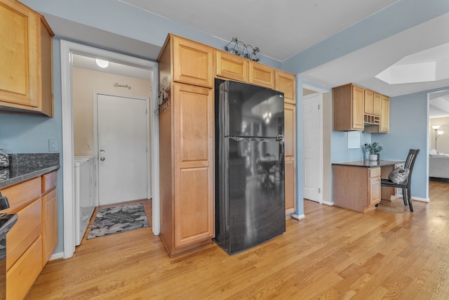 kitchen with light wood finished floors, baseboards, light brown cabinetry, a skylight, and freestanding refrigerator