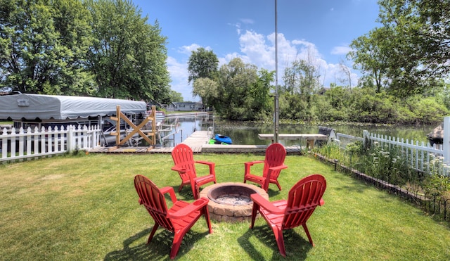 view of yard featuring a fire pit, a boat dock, a water view, and fence