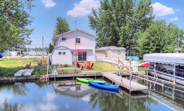 dock area featuring a lawn, a water view, and fence