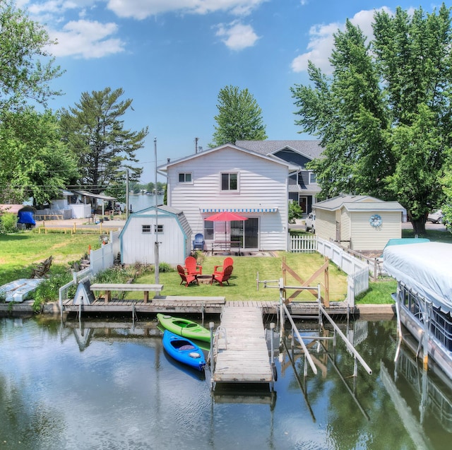 view of dock featuring a water view, a fenced backyard, and a lawn