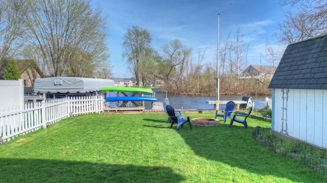 view of yard featuring a water view, fence, and a fire pit