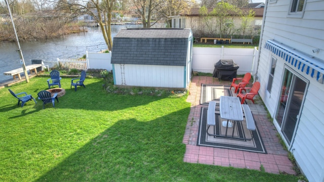 view of yard with a water view, a shed, fence, and an outdoor structure