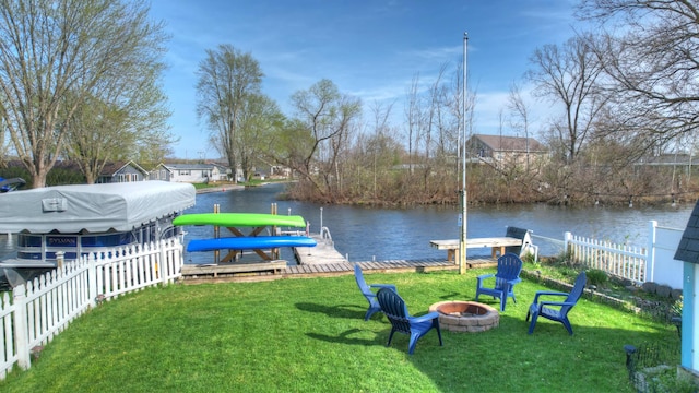 dock area with a water view, an outdoor fire pit, fence, and a yard