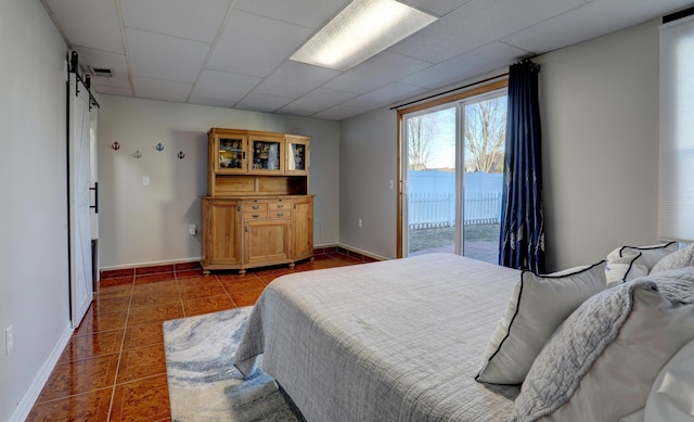 bedroom with a barn door, visible vents, dark tile patterned flooring, access to outside, and a paneled ceiling