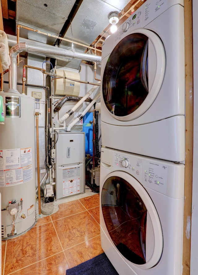 washroom with water heater, laundry area, light tile patterned floors, and stacked washing maching and dryer