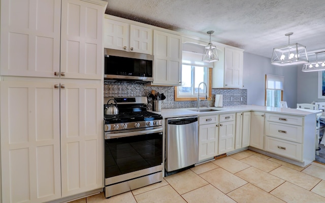 kitchen featuring tasteful backsplash, white cabinets, appliances with stainless steel finishes, a peninsula, and a sink