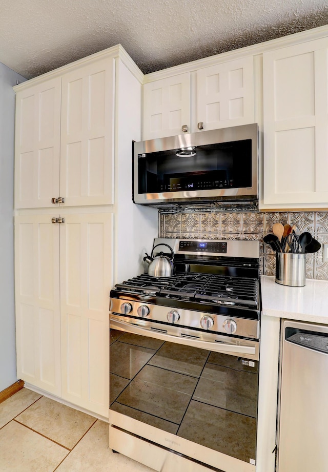 kitchen with light tile patterned floors, stainless steel appliances, light countertops, decorative backsplash, and white cabinets