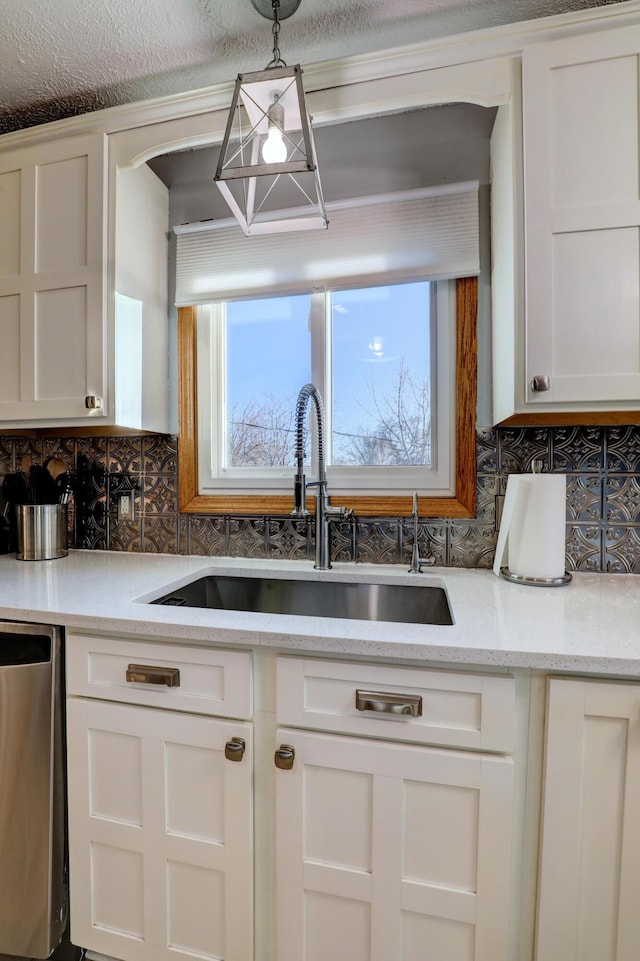 kitchen with a sink, white cabinetry, backsplash, dishwasher, and decorative light fixtures