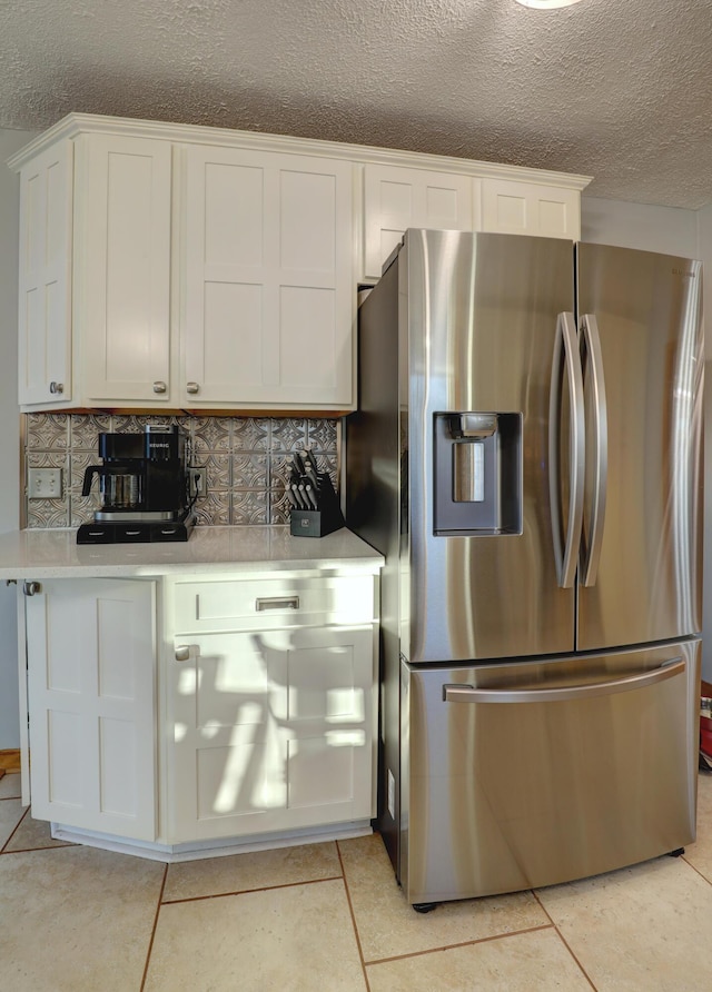 kitchen featuring light countertops, decorative backsplash, white cabinets, and stainless steel fridge with ice dispenser