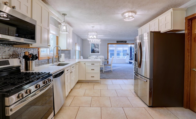 kitchen featuring a peninsula, appliances with stainless steel finishes, white cabinets, and a sink