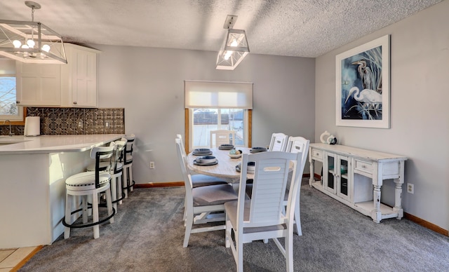 dining space with a chandelier, carpet floors, a textured ceiling, and a healthy amount of sunlight