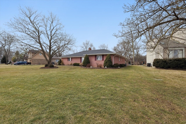 exterior space with a front lawn, a chimney, and brick siding