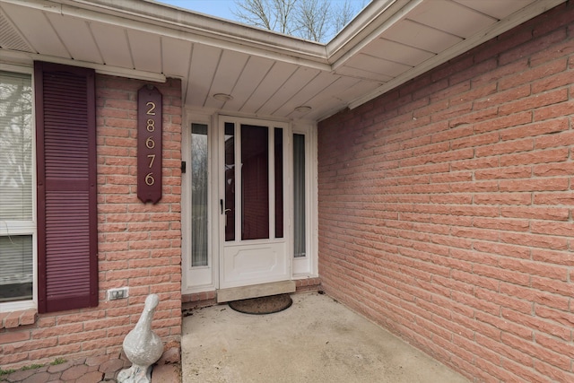 view of exterior entry featuring brick siding