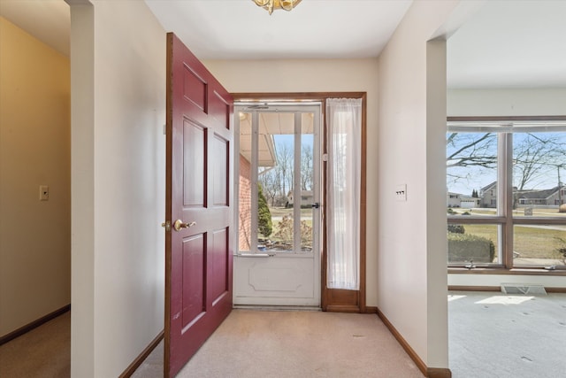 entryway with baseboards, visible vents, and light colored carpet