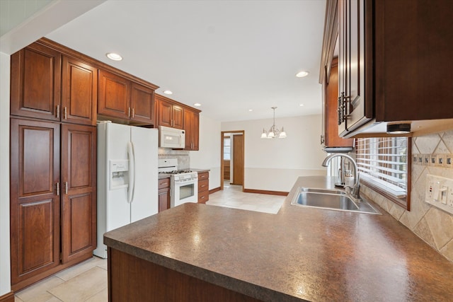 kitchen featuring tasteful backsplash, dark countertops, a sink, white appliances, and a peninsula