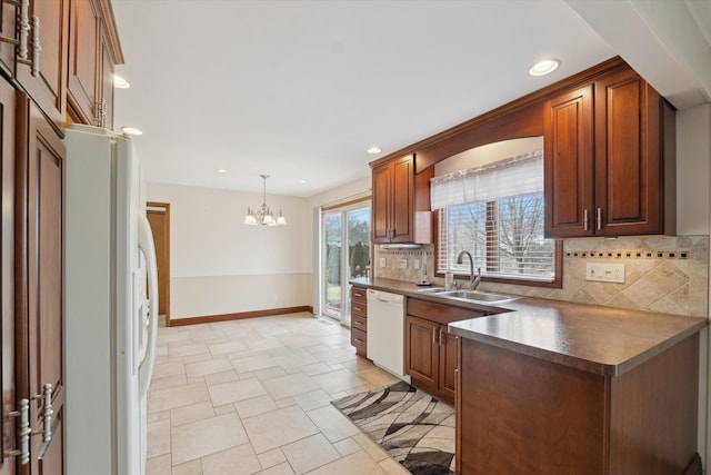 kitchen featuring white appliances, tasteful backsplash, baseboards, dark countertops, and a sink