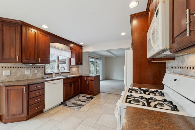 kitchen with white appliances, tasteful backsplash, a peninsula, a sink, and recessed lighting